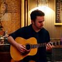 A musician playing an acoustic guitar in the corner of the cafe.